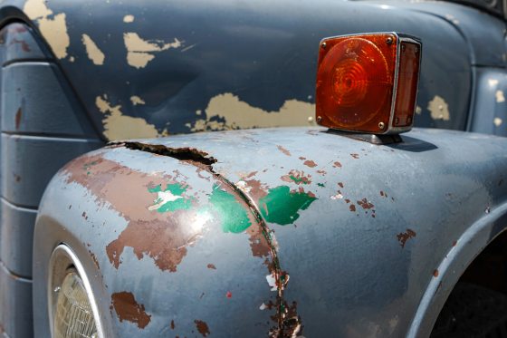 A close up image of a truck wheel well with many layers of peeling paint.